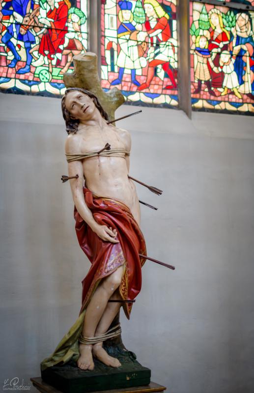Statue of St. Sebastian in the Church of St. Martin in Landhust. In the background a decorated window with scenes from the catholic tradition