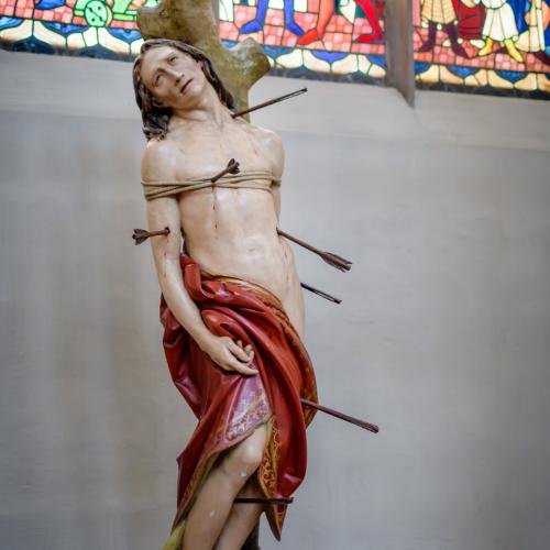 Statue of St. Sebastian in the Church of St. Martin in Landhust. In the background a decorated window with scenes from the catholic tradition
